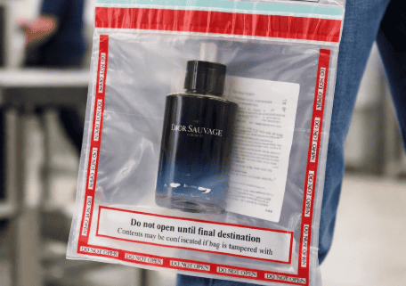 Traveler holding a sealed duty-free STEB bag with cologne inside at airport security checkpoint