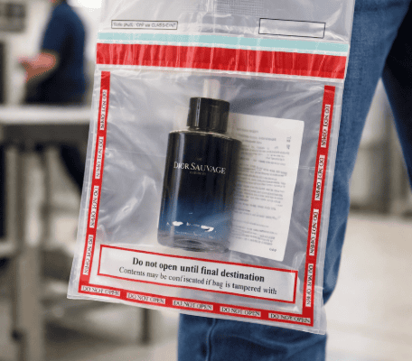 Traveler holding a sealed duty-free STEB bag with cologne inside at airport security checkpoint