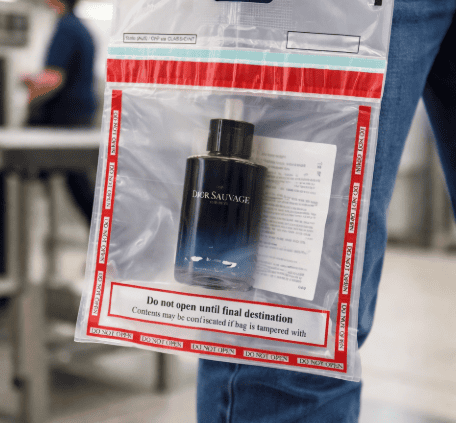 Traveler holding a sealed duty-free STEB bag with cologne inside at airport security checkpoint